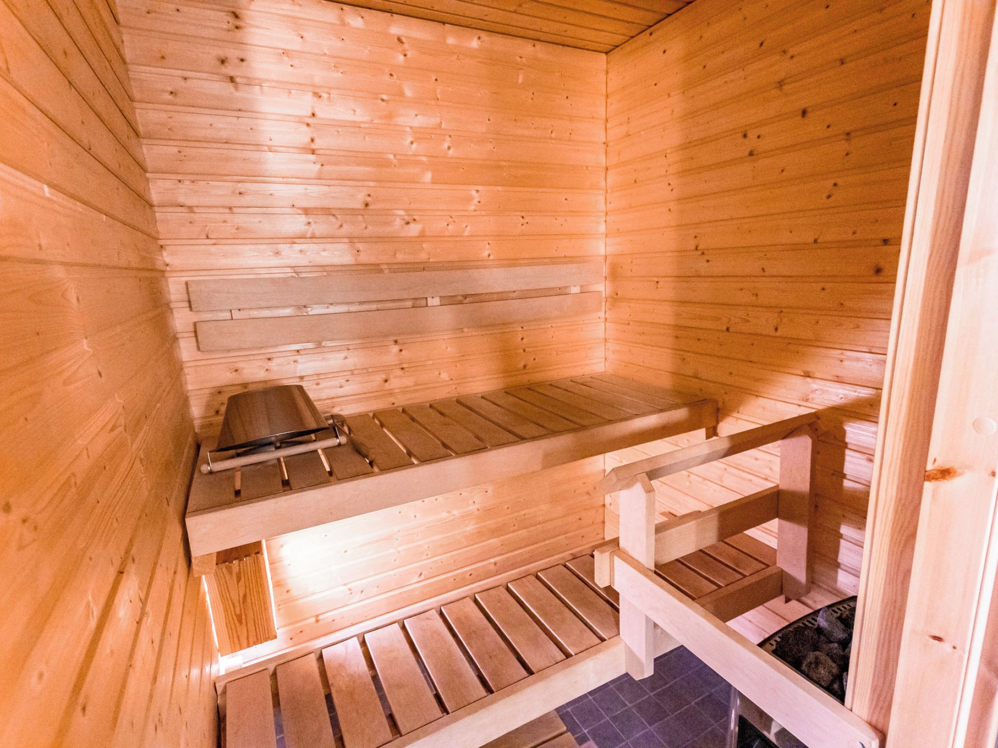 Una sauna con bancos de madera y un banco con un perchero para toallas.