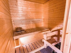 A sauna with wooden benches and a bench with a towel rack. - Nordic chalet 9402 by Interhome (Ylläsjärvi)
