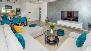 A modern living room with a sofa set, a coffee table, and a flat-screen TV mounted on a textured wall. - Rest for the soul by Interhome (Imotski)