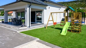 A modern house with a patio, a swing set, and a slide. - Rest for the soul by Interhome (Imotski)