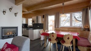 Ein gemütliches Blockhaushaus-Interieur mit Kamin, Holzespeisesaal, Stühlen und einer Couch.