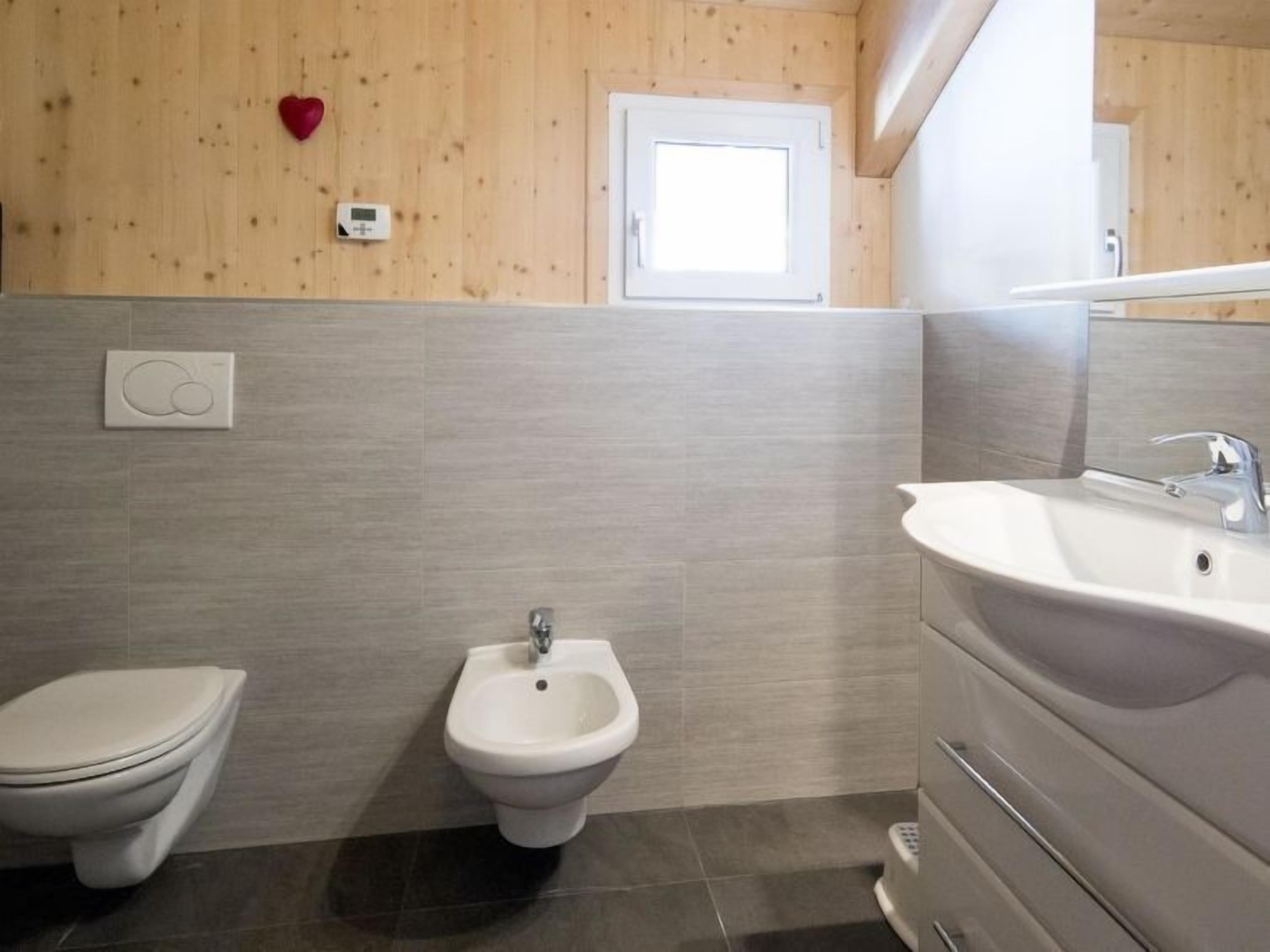 Une salle de bain moderne équipée de toilettes, d’un bidet et d’un grand lavabo.