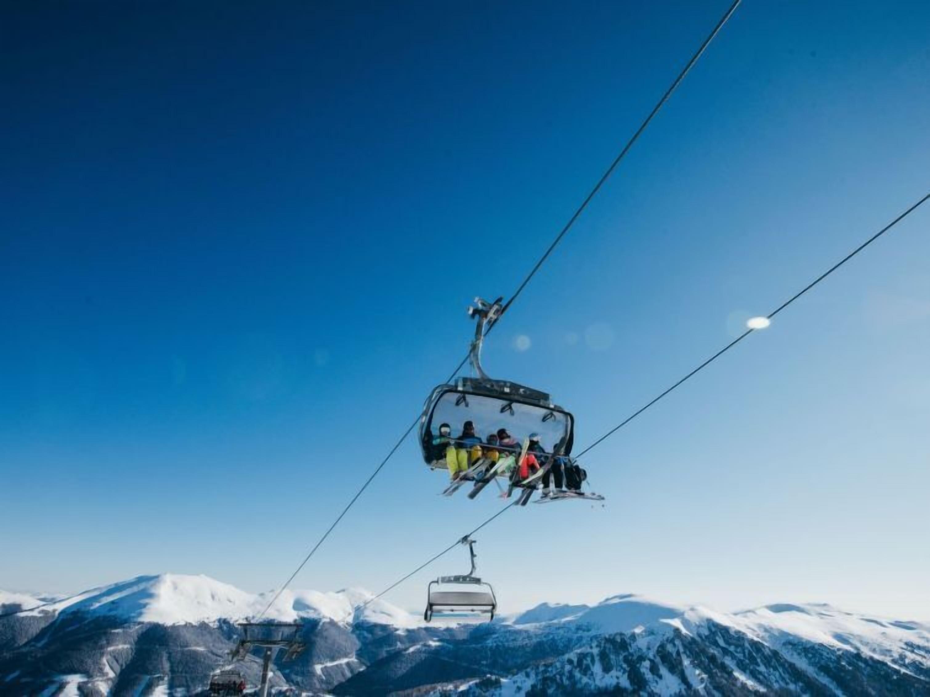Un téléphérique transportant des skieurs au-dessus d’un paysage montagneux.