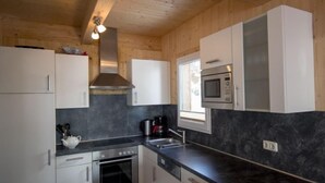 Eine moderne Küche mit weißen Schränken, einer schwarzen Arbeitsplatte, Edelstahlgeräten und einem Fenster, das für natürliches Licht sorgt.