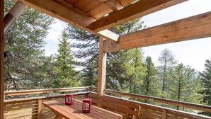 Eine Holzterrasse mit Tisch und Stühlen mit Blick auf einen Wald.
