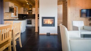 A modern interior with a central fireplace, wooden furniture, and a kitchen area. - #9 mit IR-Sauna & Sprudelwanne Innen by Interhome (Turracher Höhe)