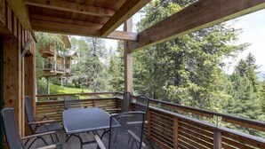 A wooden deck with a table and chairs, overlooking a forested area. - #9 mit IR-Sauna & Sprudelwanne Innen by Interhome (Turracher Höhe)