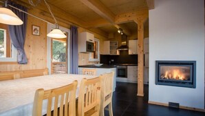 A cozy wooden cabin interior with a dining area, kitchen, and a fireplace. - #9 mit IR-Sauna & Sprudelwanne Innen by Interhome (Turracher Höhe)