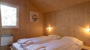 A wooden cabin room with a bed, a window, and a wall-mounted light fixture. - #4 mit IR-Sauna & Sprudelwanne innen by Interhome (Turracher Höhe)