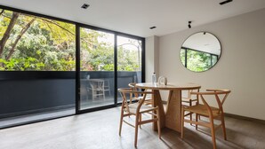 A room with a large window, a round mirror, and a round table with chairs. - Wynwood House Sinaloa (Mexico City)