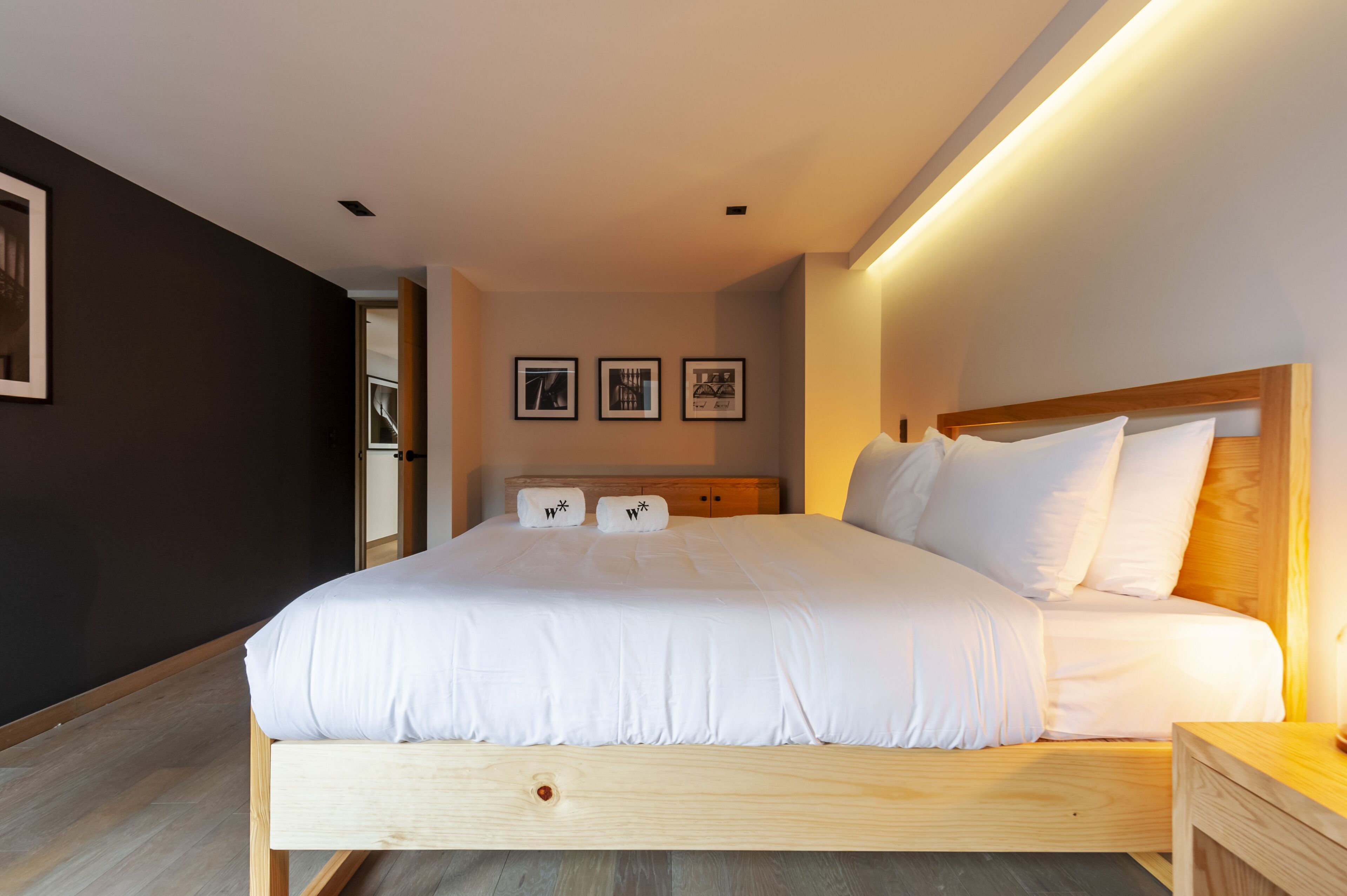 Une chambre à coucher moderne avec un grand lit, une tête de lit en bois et des tables de chevet.