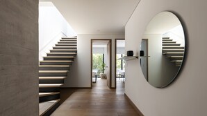 Ein modernes Interieur mit einer Holztreppe, einem großen Spiegel und Blick ins Freie.
