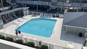 A rooftop swimming pool with white railings, lounge chairs, and a building with multiple balconies in the background. - Family-friendly beach condo, Indian Beach, NC (Salter Path)