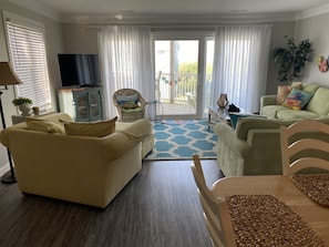 Un salon comprenant un canapé, un fauteuil, un téléviseur et une table à manger.