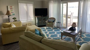 A living room with a sofa, armchair, and a television on a cabinet. - Family-friendly beach condo, Indian Beach, NC (Salter Path)