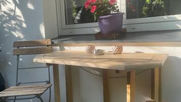Una mesa de madera con dos tazas y platillos, una silla y una planta en maceta sobre un alféizar.