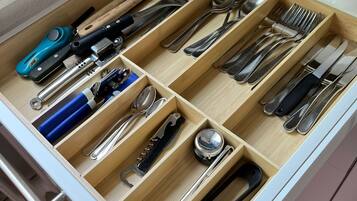A kitchen drawer with multiple compartments containing various utensils and tools.