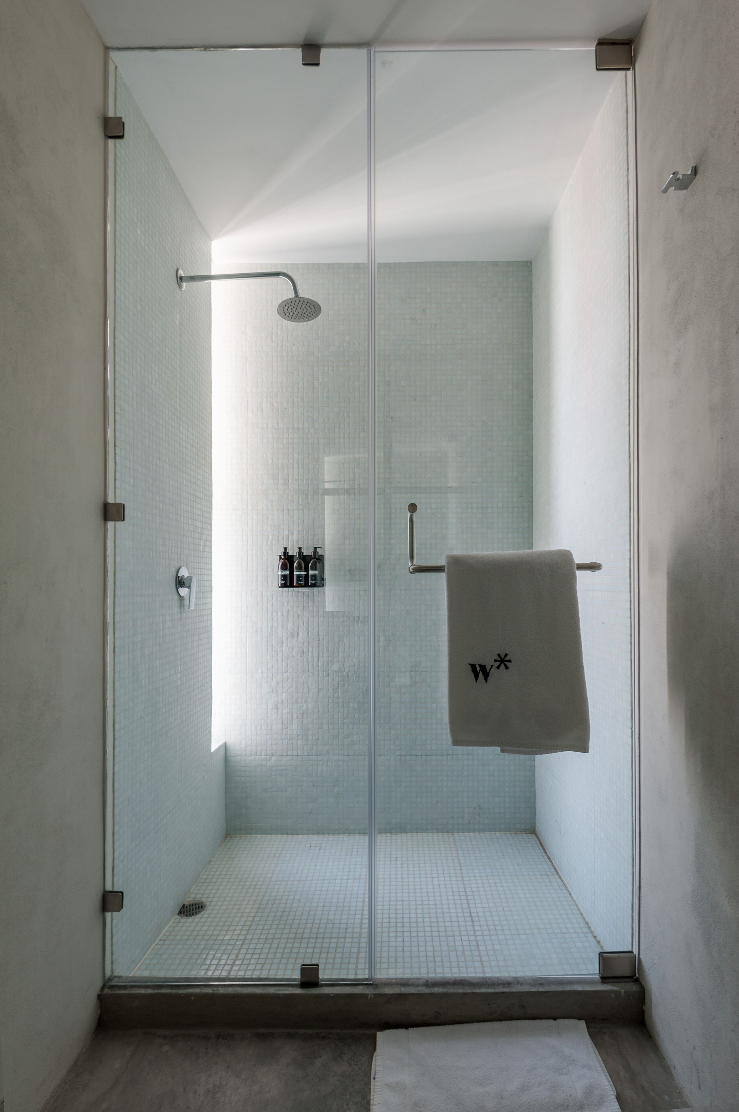 A glass-enclosed shower with a white towel hanging on the door.