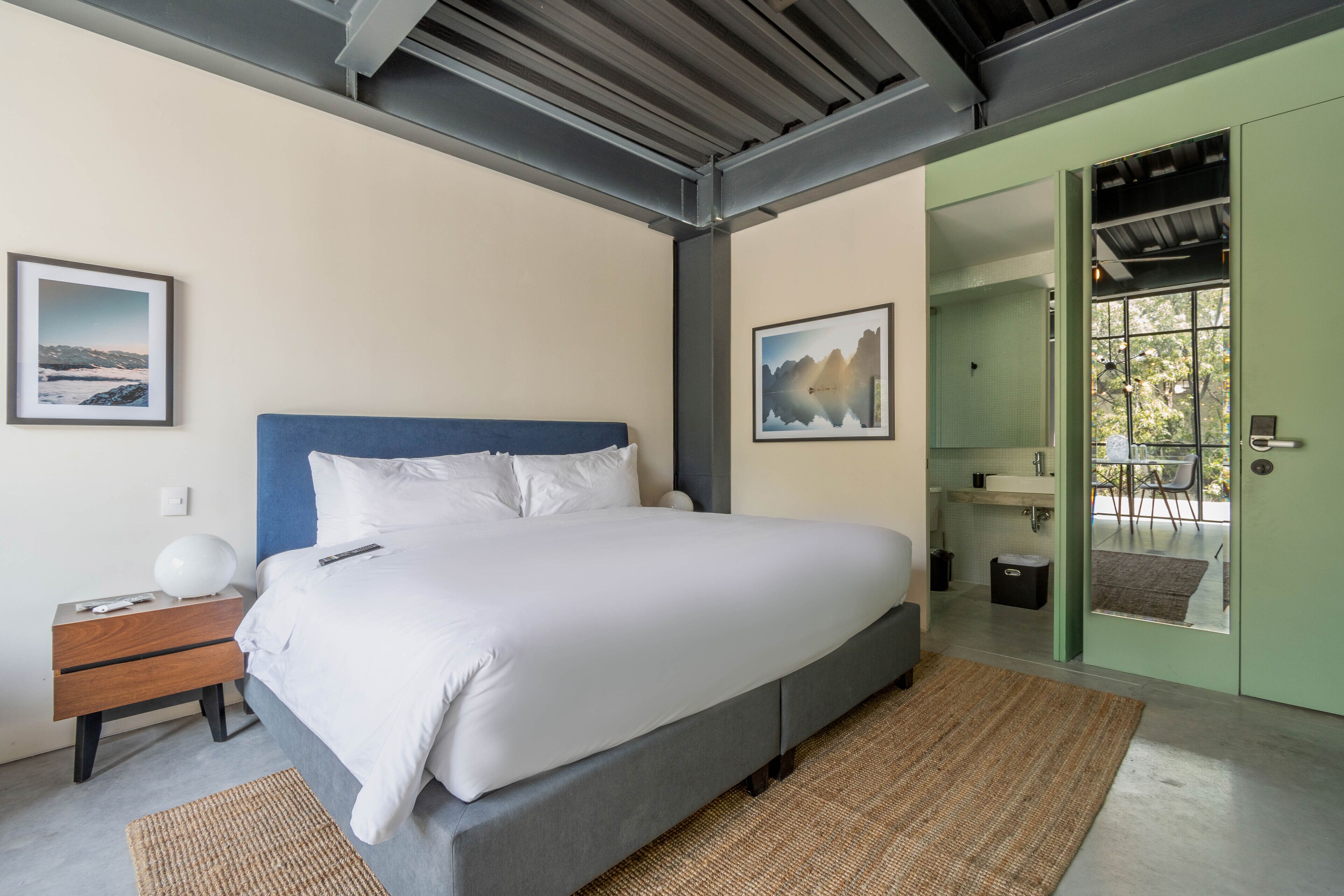 Un dormitorio moderno con una cama grande, una mesita de noche de madera y dos cuadros enmarcados en la pared.