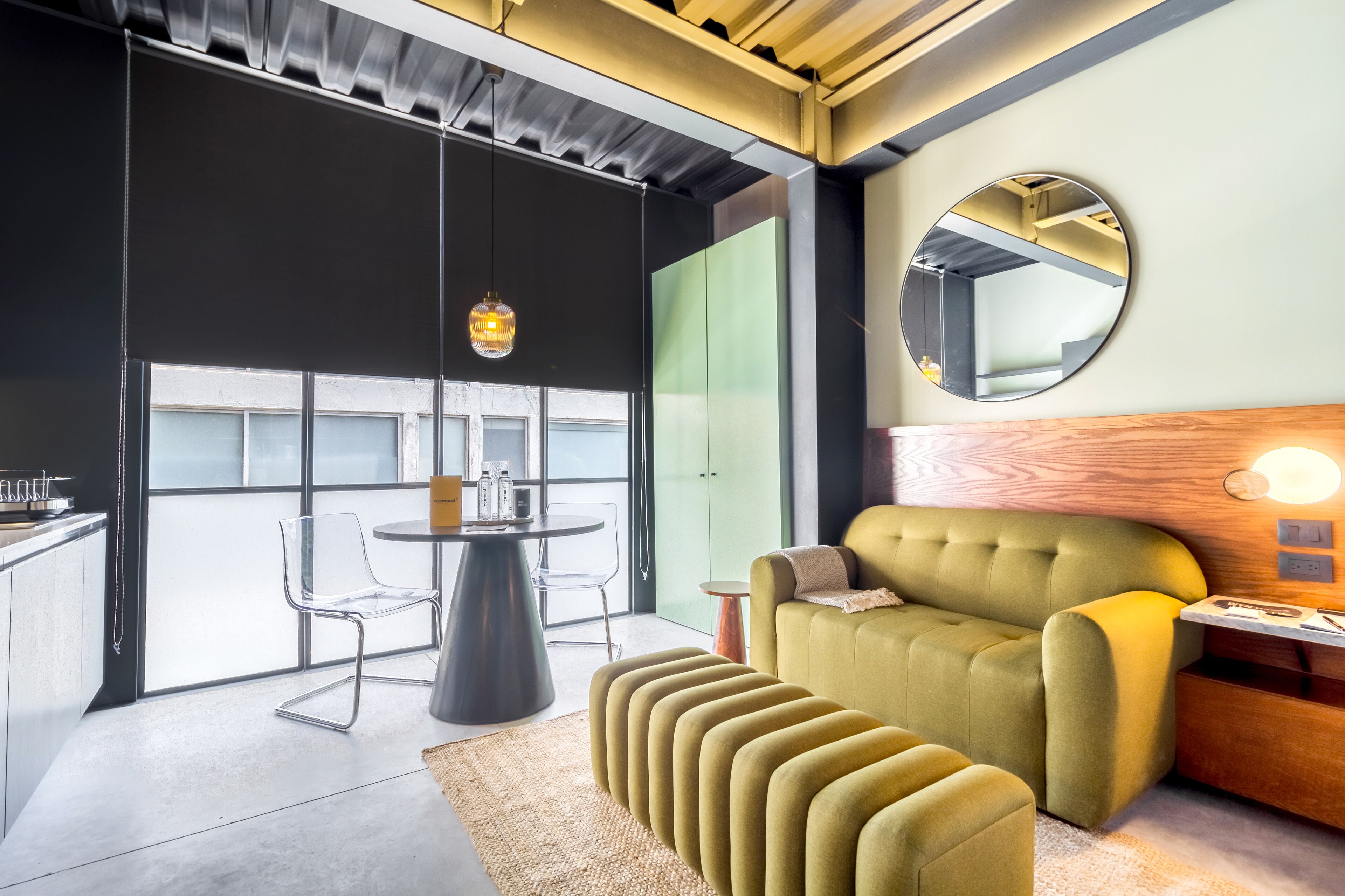 A modern living room with a green sofa, a round table, and a mirror on the wall.