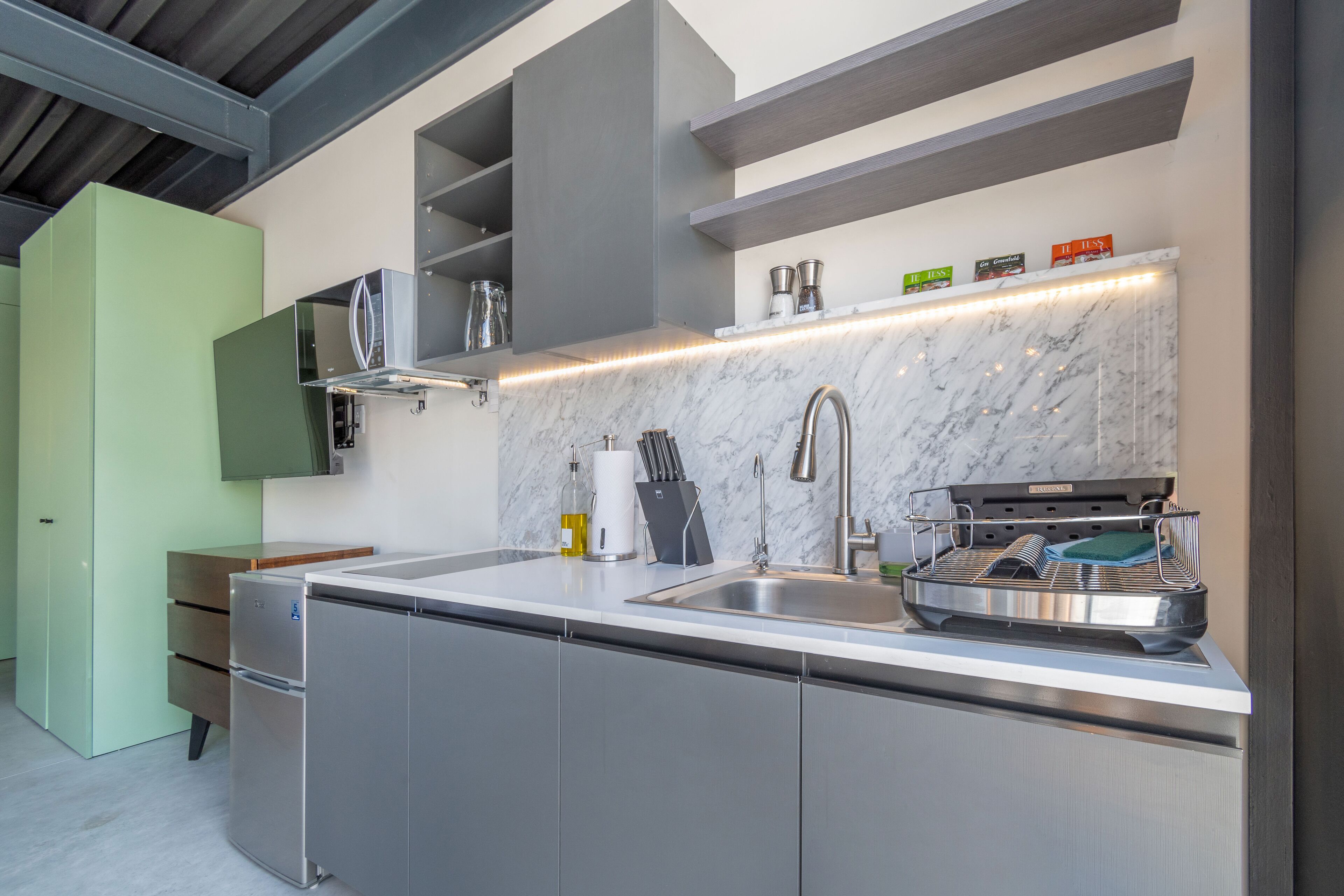 A modern kitchen with a stainless steel sink, a built-in oven, and a marble backsplash.
