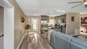 Una cocina moderna con refrigerador, microondas y comedor con mesa y sillas.