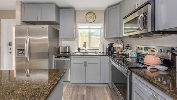 Una cocina moderna con electrodomésticos de acero inoxidable, armarios grises y encimera de granito.