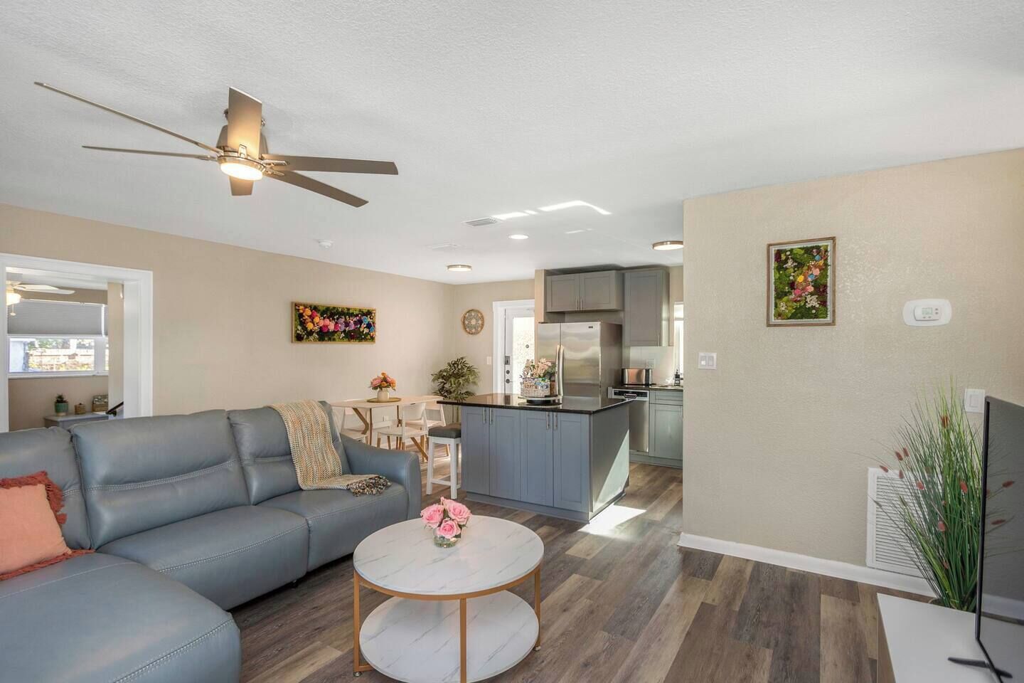 A modern living room with a grey sofa, a round coffee table, and a ceiling fan.