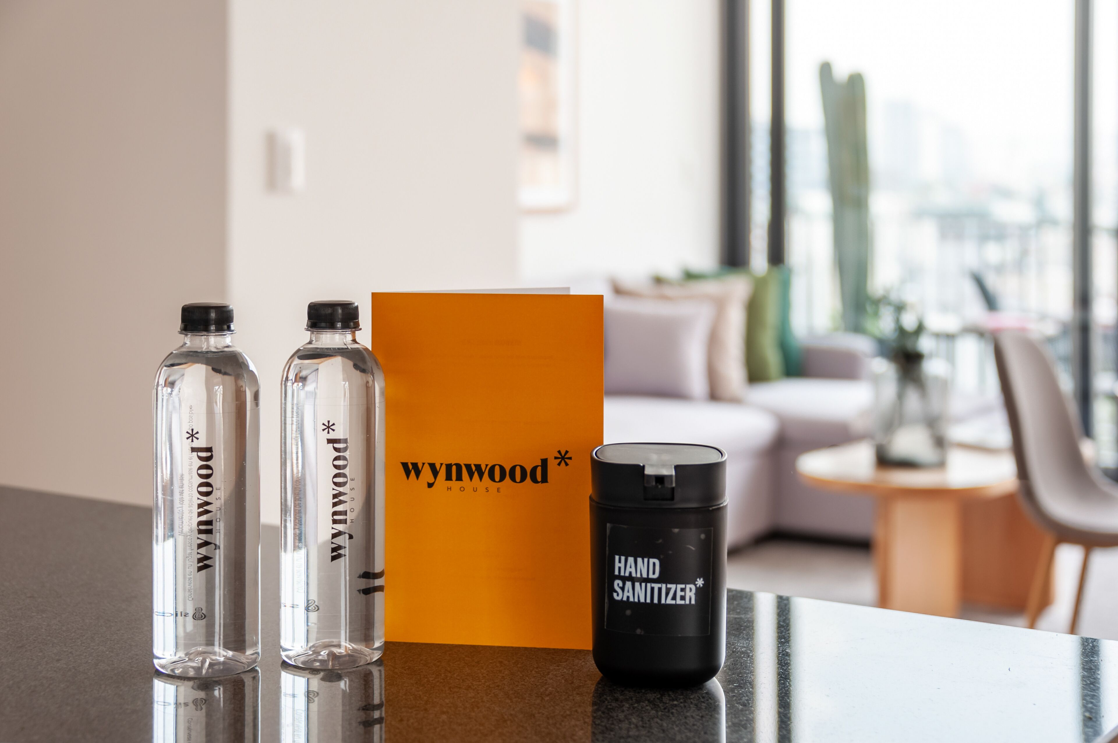 A table with two clear glass bottles, an orange box, and a black hand sanitizer container.