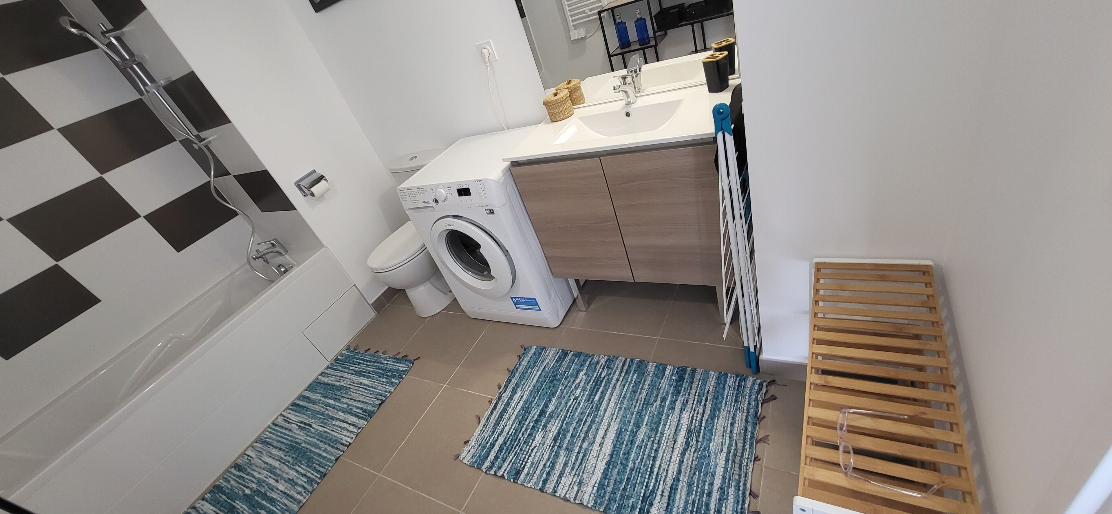 A compact bathroom with a washing machine, a sink, and a toilet.