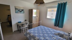 Quarto com cama, escrivaninha, cadeira, guarda-roupa e janela com cortinas.