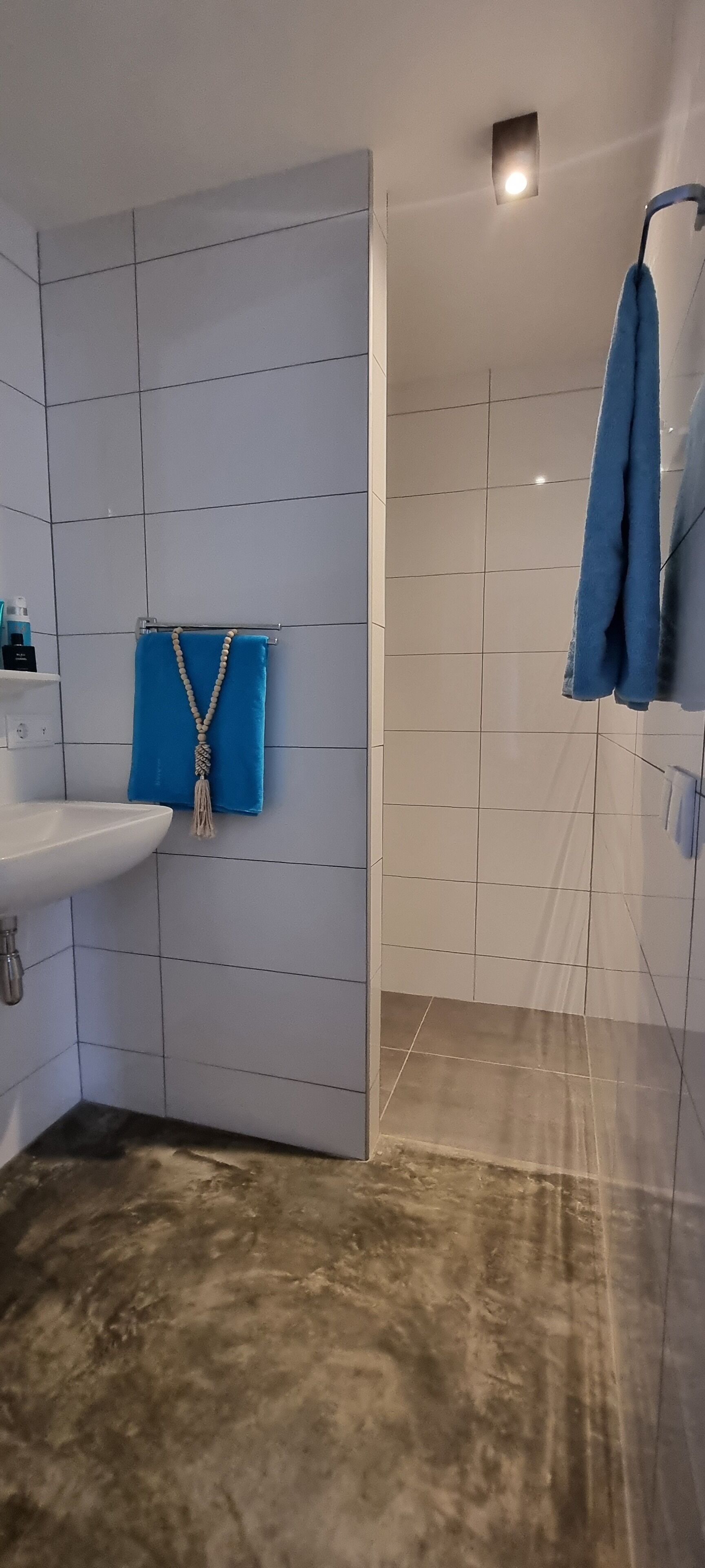 Un baño con un lavamanos blanco, una toalla azul y una zona de ducha.