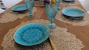 A dining table set with blue plates, gold cutlery, and blue glassware. - Kas Azul - Water front with private pool (Kralendijk)