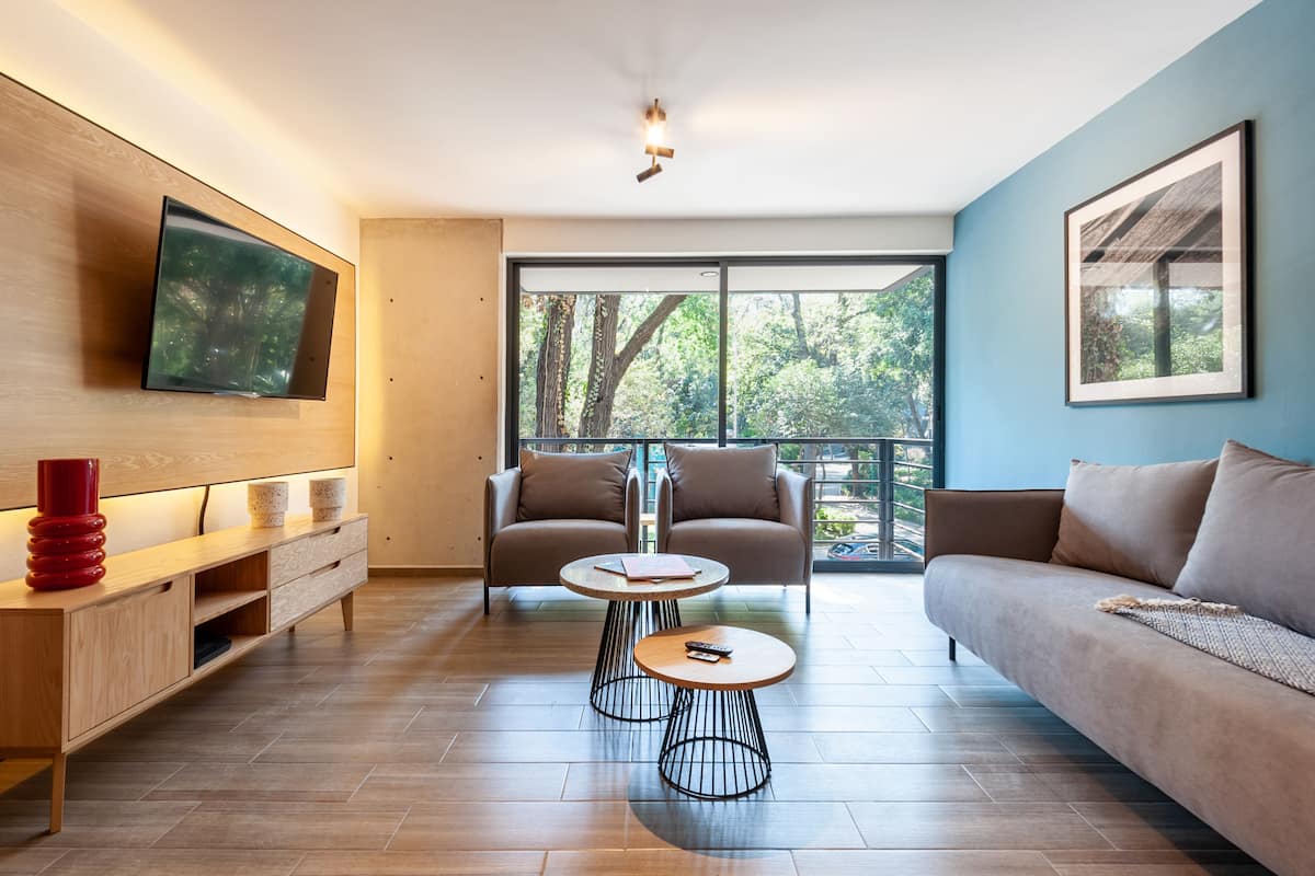 Una sala de estar moderna con un televisor de pantalla plana, dos sofás, una mesa de centro y un mueble bajo de madera.
