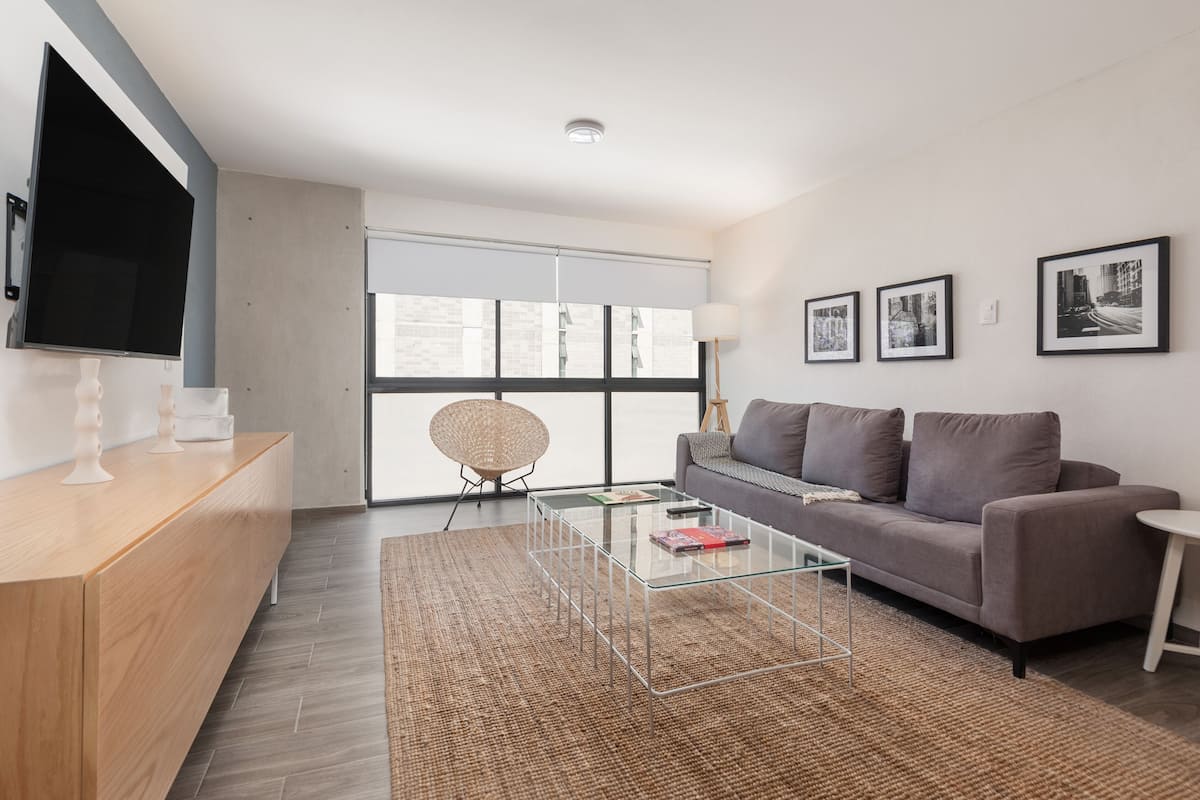 Una sala de estar moderna con un sofá, una mesa de centro y un televisor montado en la pared.