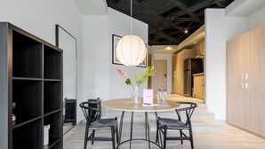 Een moderne eethoek met een ronde tafel, vier stoelen, een vaas met bloemen en een hanglamp.