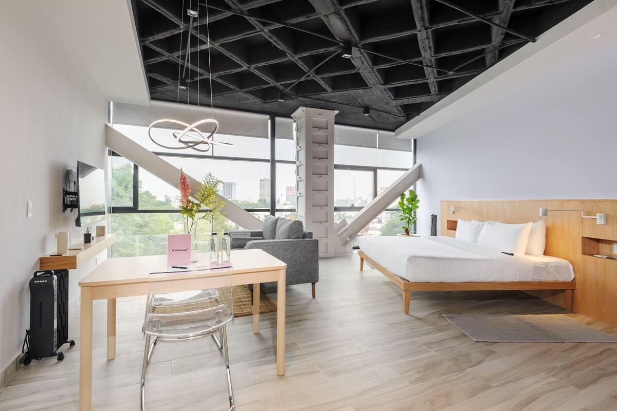 Une chambre d’hôtel moderne dotée d’un grand lit, d’un bureau, d’une chaise, d’un canapé et offrant une vue sur la ville.