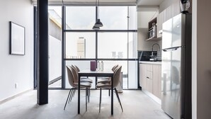 Een moderne keuken met een groot raam, een eettafel met stoelen en een koelkast.