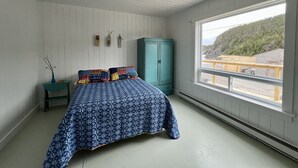 A bedroom with a bed, a window, a wardrobe, and a small table with a vase. - Oceanside Artists Cottage, Dunfield, Trinity Bay (Dunfield)