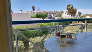 Een balkon met een tafel gedekt voor twee personen, inclusief een fles wijn en twee glazen.