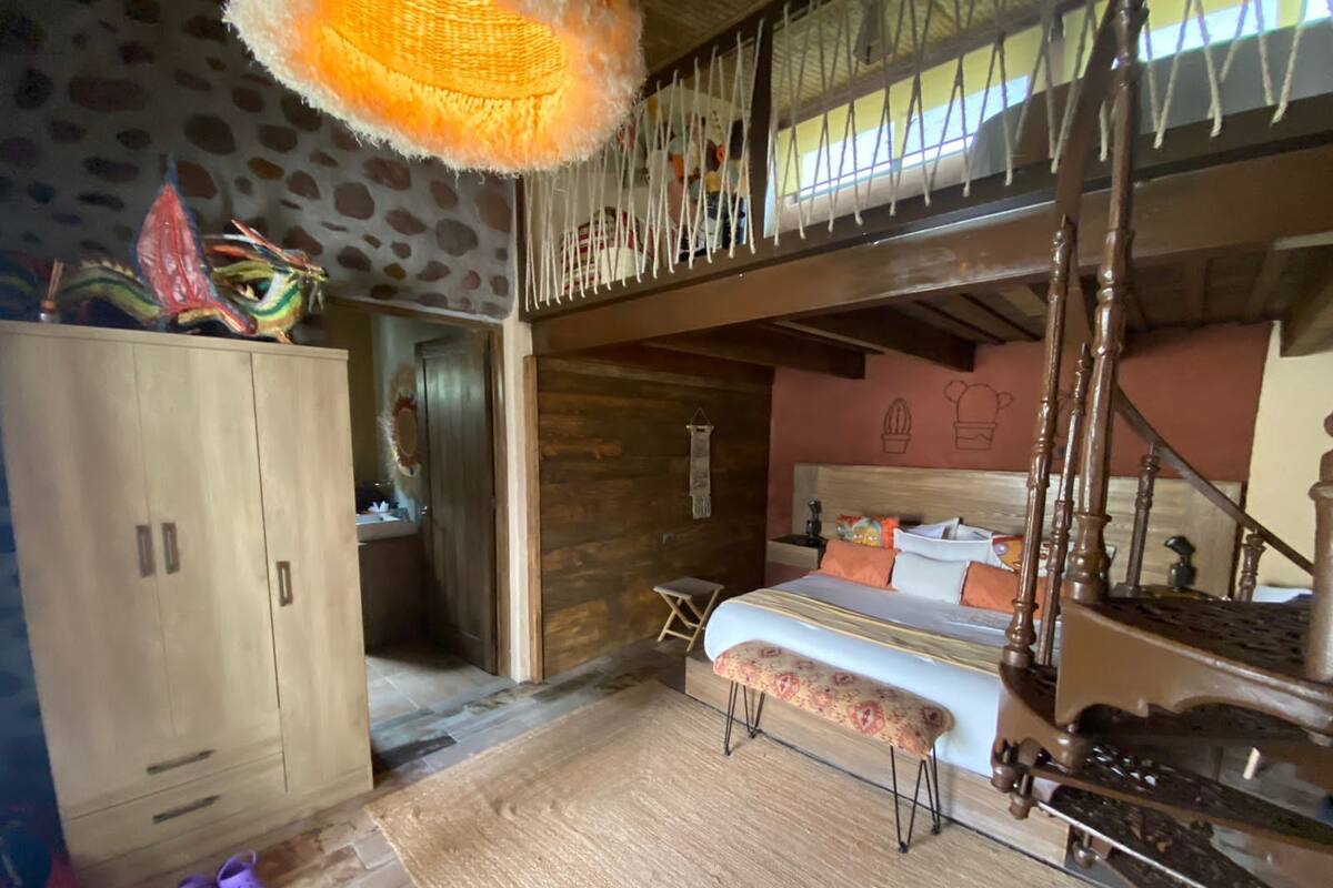 Una habitación con cama, armario de madera y un banco.