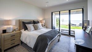Une chambre moderne avec un grand lit, des lampes de chevet, une table de chevet et une vue sur l’extérieur grâce à une porte-fenêtre coulissante.
