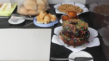 A buffet table with various baked goods including a chocolate cake with sprinkles, a bundt cake, and several rolls.