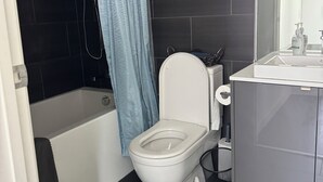 A bathroom with a white toilet, a bathtub, and a shower area.