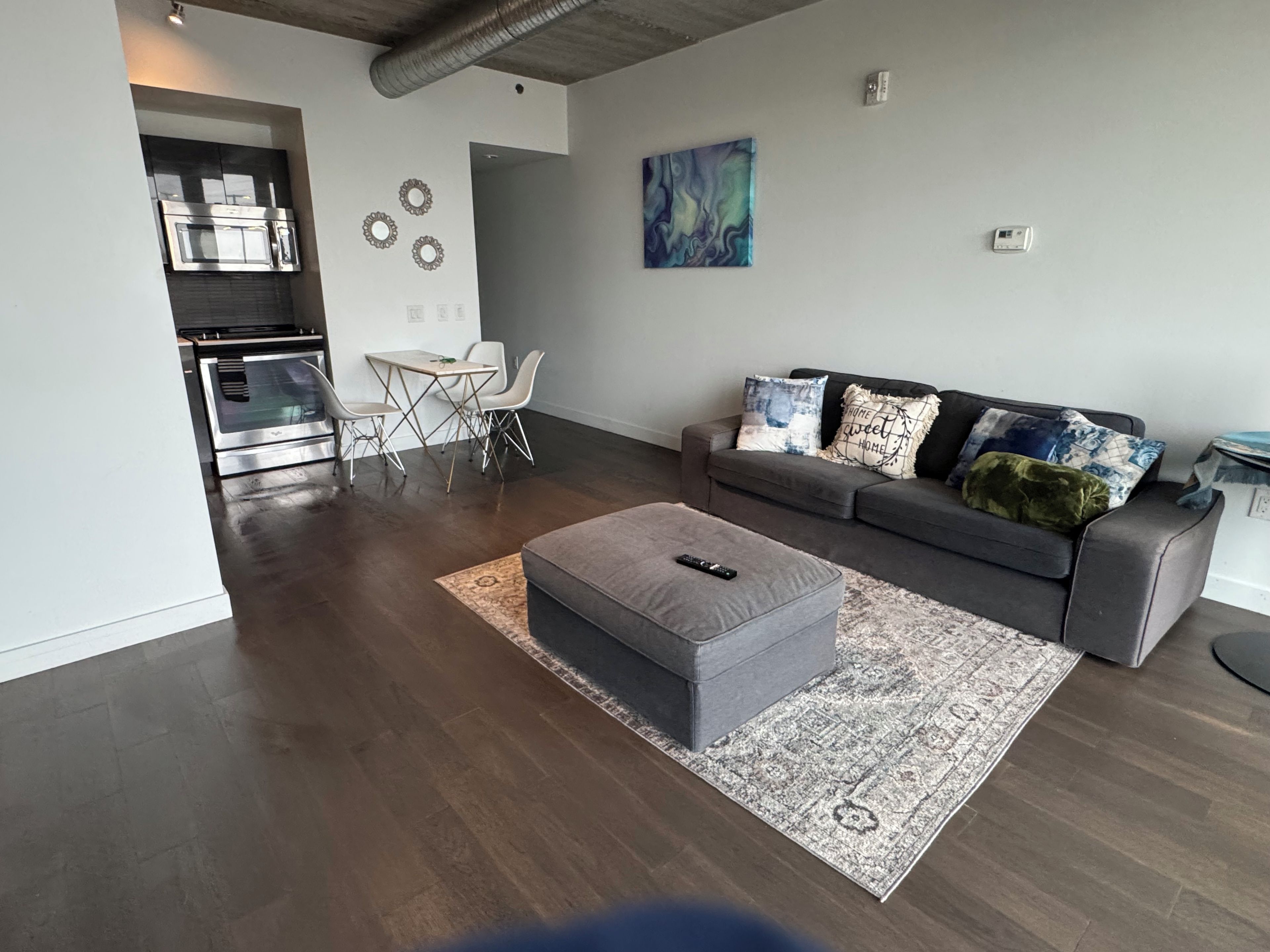A modern living room with a grey sofa, a coffee table, and a dining area with a table and chairs.
