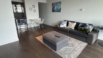 A modern living room with a grey sofa, a coffee table, and a dining area with a table and chairs.