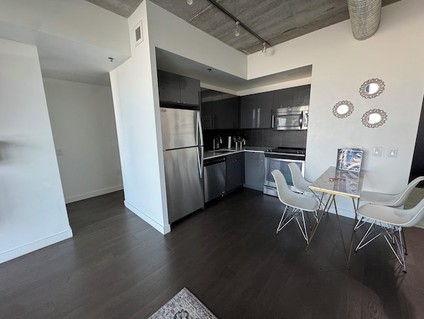 A modern kitchen with stainless steel appliances, a dining area with two chairs, and a small table.