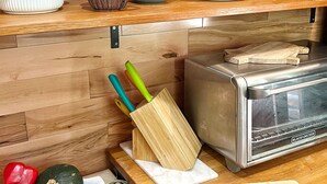 A kitchen counter with a toaster, a cutting board, and various kitchen utensils. - 1960 Mid-Century Modern Nature Retreat (Cambridge)