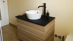 Ein Badezimmer mit einem weißen Waschbecken, einem schwarzen Wasserhahn und einem Spiegel darüber.