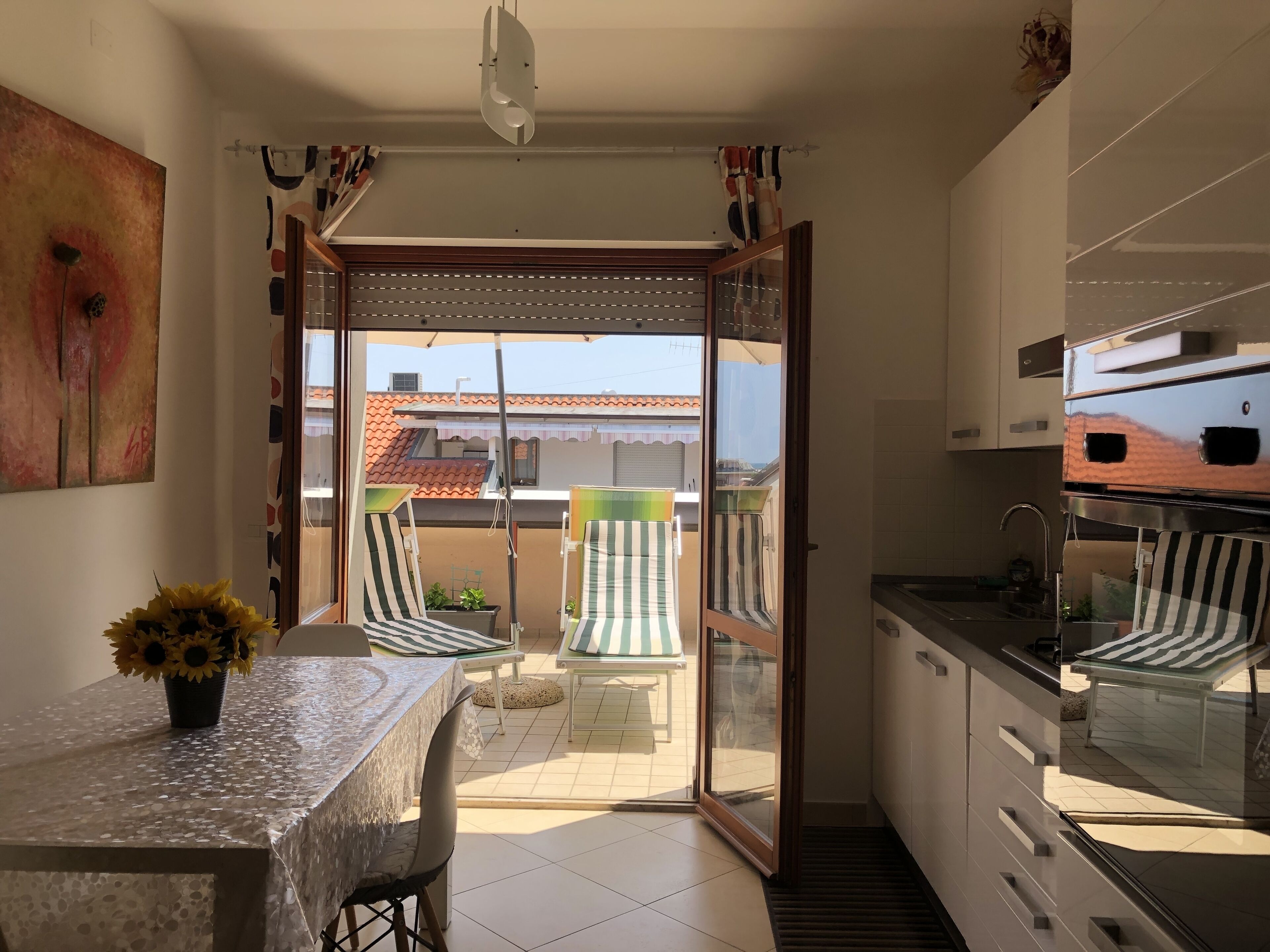 A balcony with a table and chairs, a sliding glass door, and a view of the neighborhood.